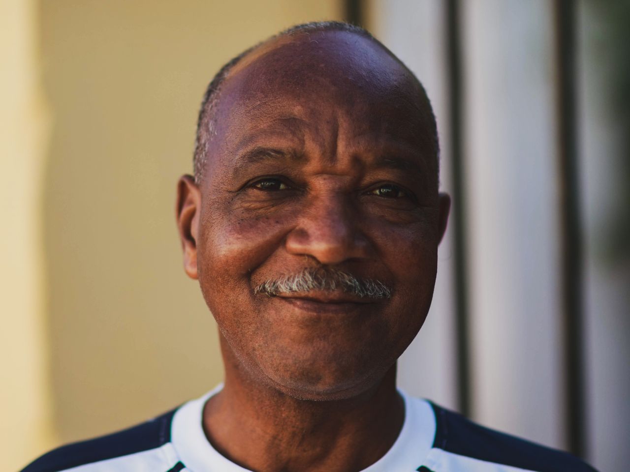 Close-up portrait of a smiling mature man with a mustache, exuding warmth and confidence.